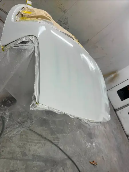 A silver body panel freshly resprayed and masked up in the spray booth