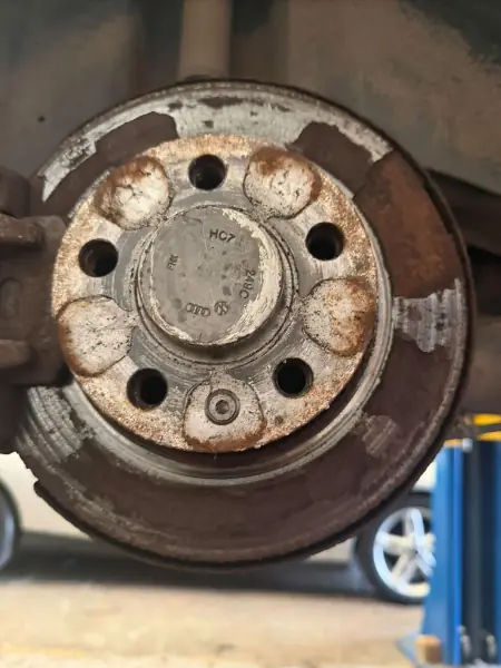 Before: a heavily corroded, rusty brake disc still on the car