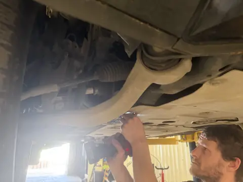 Close-up of front suspension and steering parts being worked on under a car at RPM Autocare