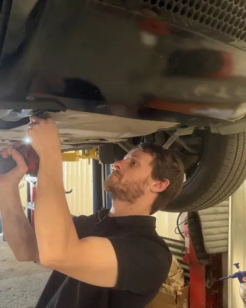 Russ working under a car on the ramp at RPM Autocare, Newton Abbot